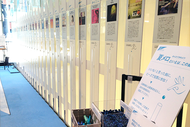 来訪者参加型の展示。パネルに付属する筒にブルーの玉を入れて投票する。